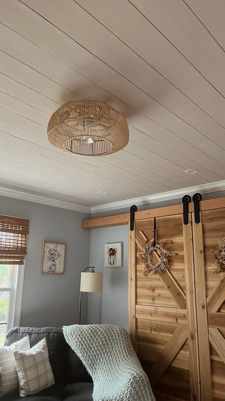 Light gray shiplap ceiling with a woven rattan pendant light hanging in a living room.