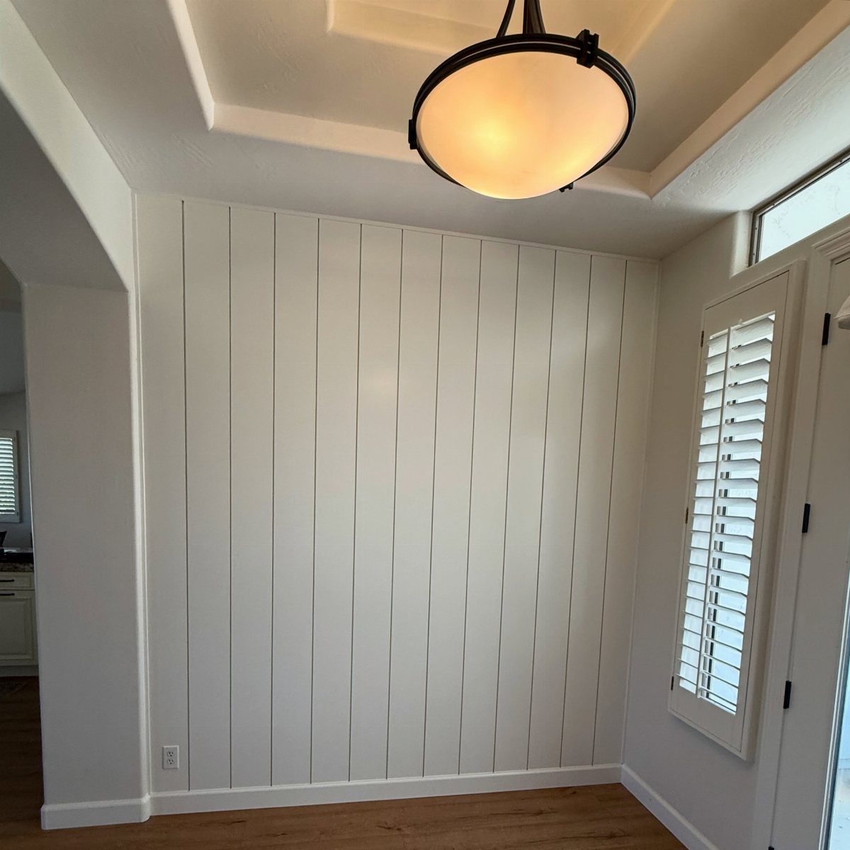 White vertical shiplap planks covering a full interior wall under a circular ceiling light.