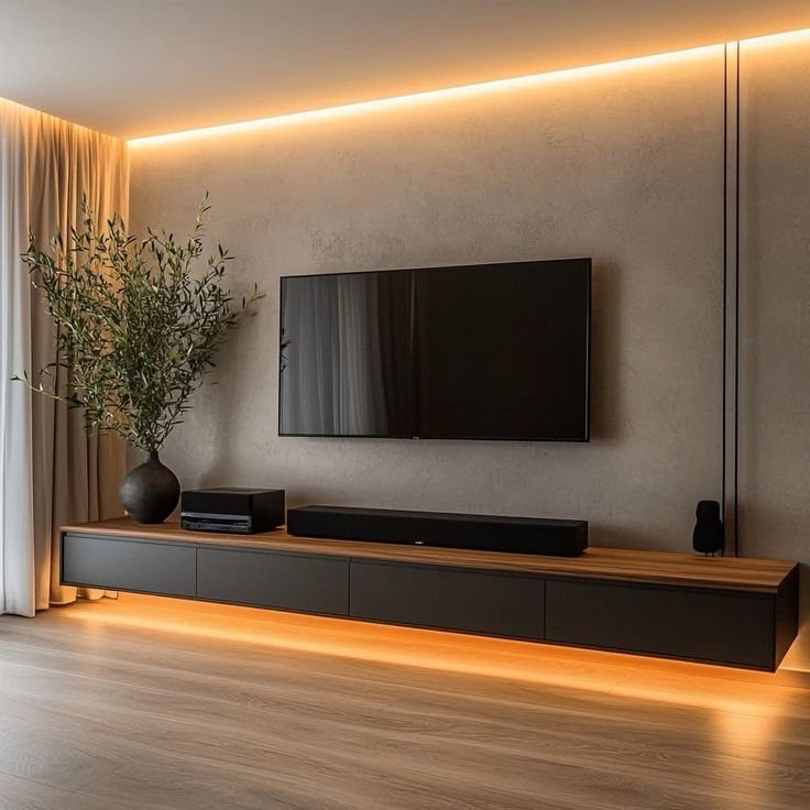 A long minimalist media console with warm LED lighting beneath a mounted television on a textured wall.