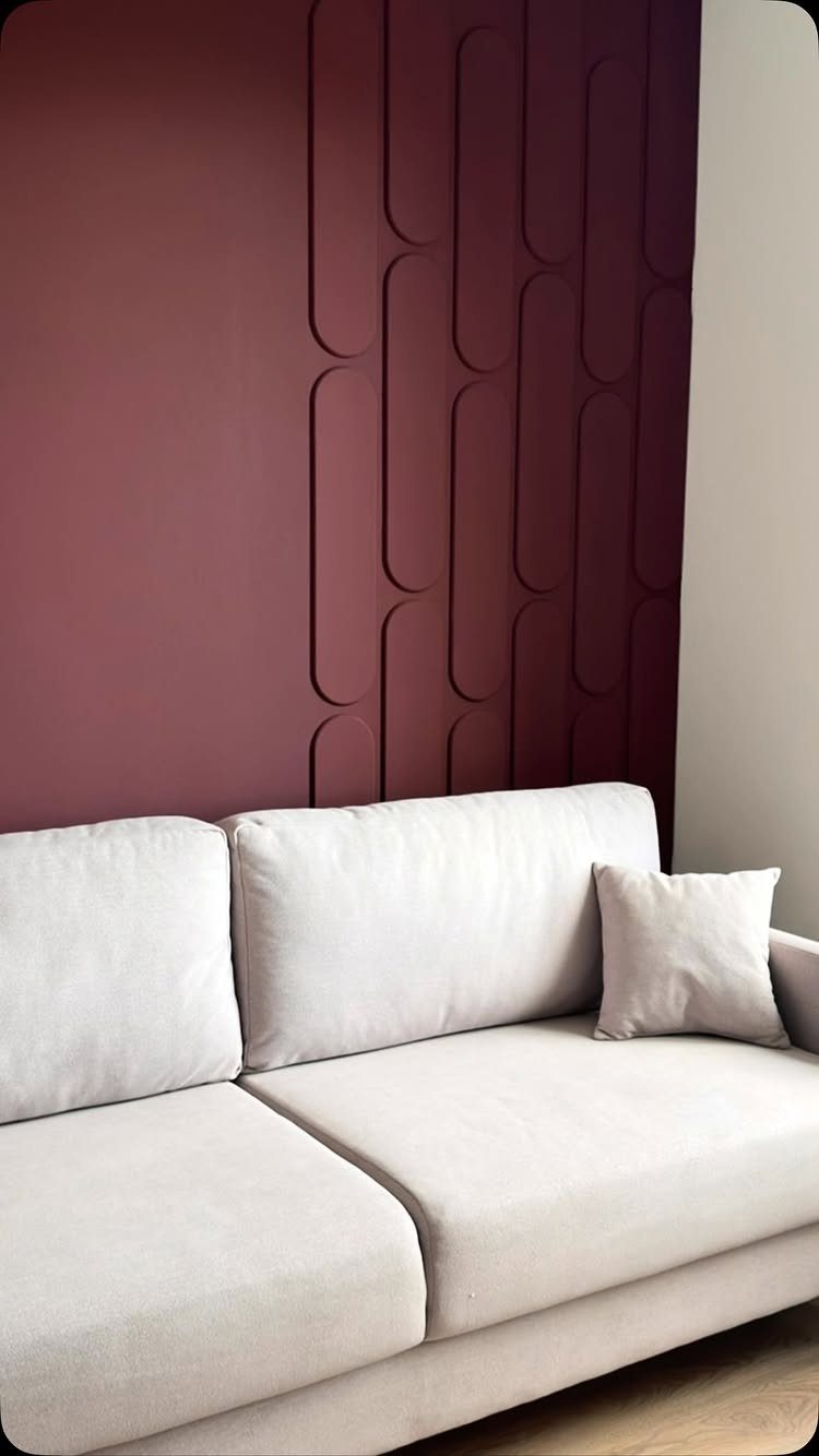 Types of Wall Paneling: 10 Styles for Any Room 3 Burgundy 3D wall panels with elongated oval patterns behind a light grey sofa.