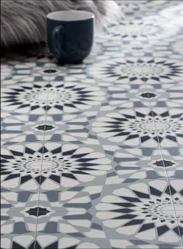 Geometric patterned vinyl floor tiles with navy, grey, and white starburst designs.