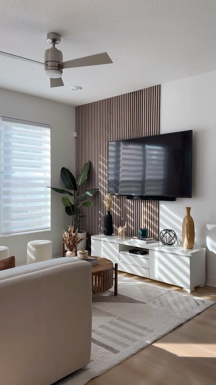 A television mounted on a vertical wood slat accent wall above a white media console.