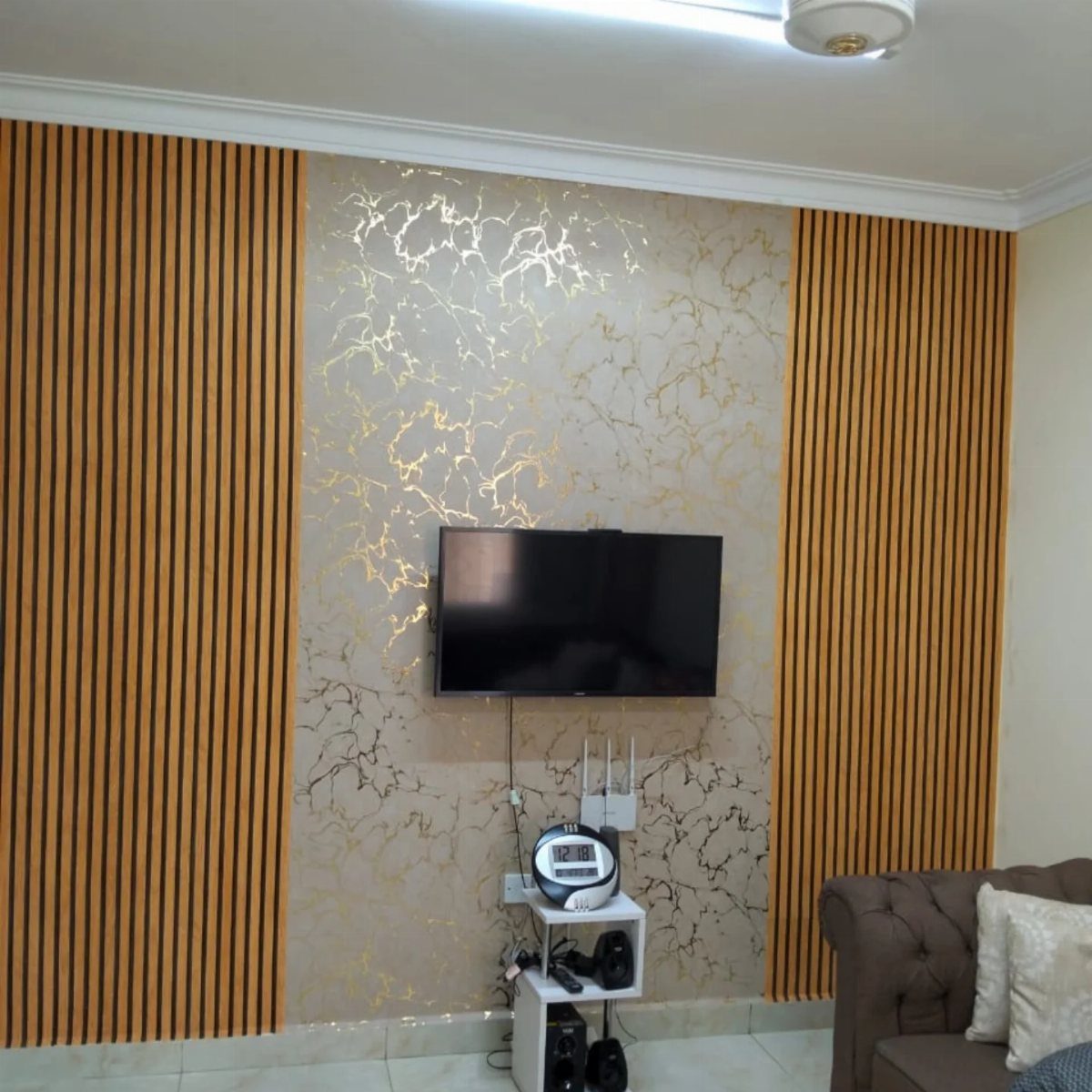 A television mounted on a marble-patterned wallpaper wall with vertical wooden slats on the sides.
