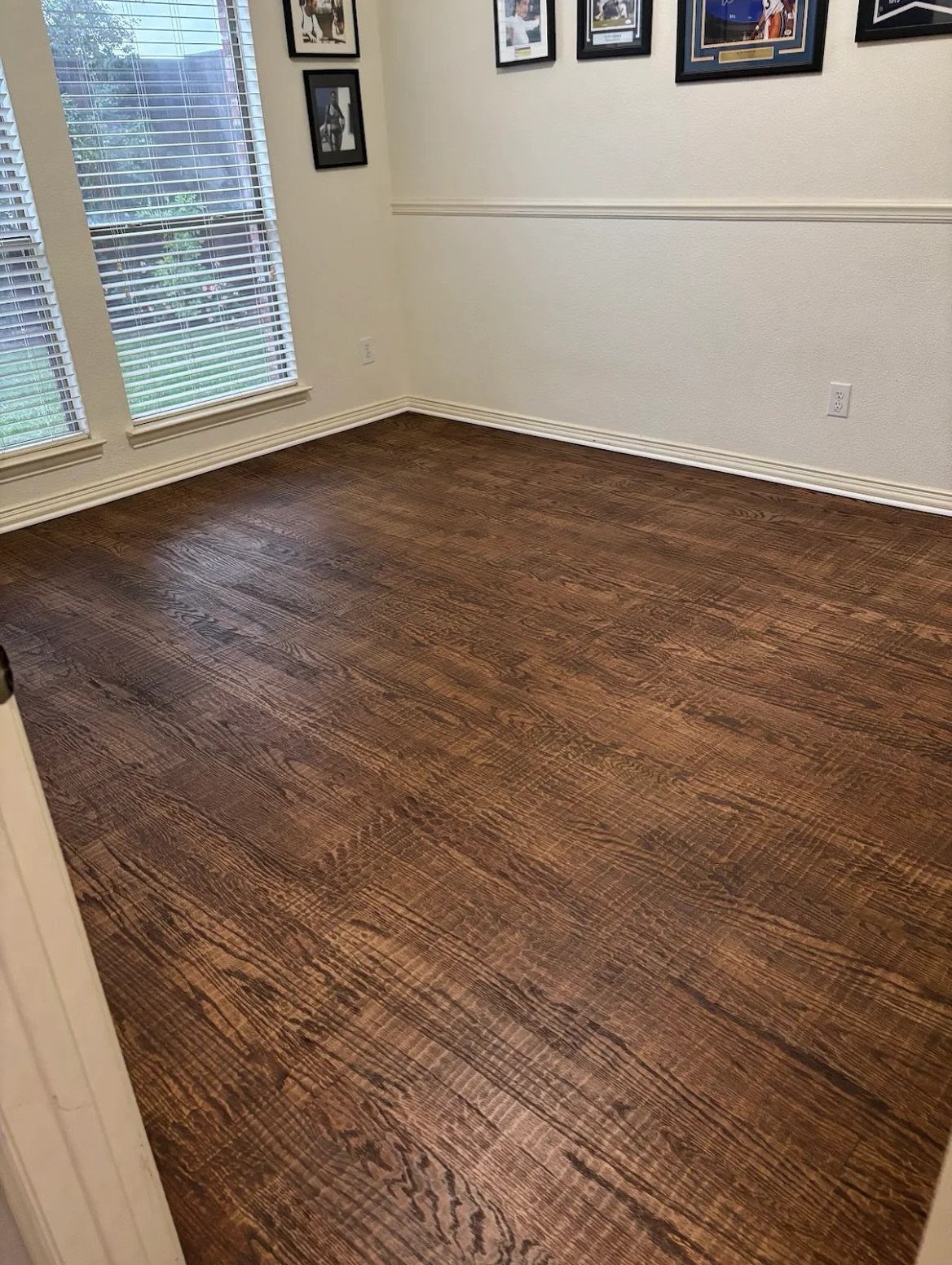 Dark brown textured wood flooring in an empty room with white walls and windows.