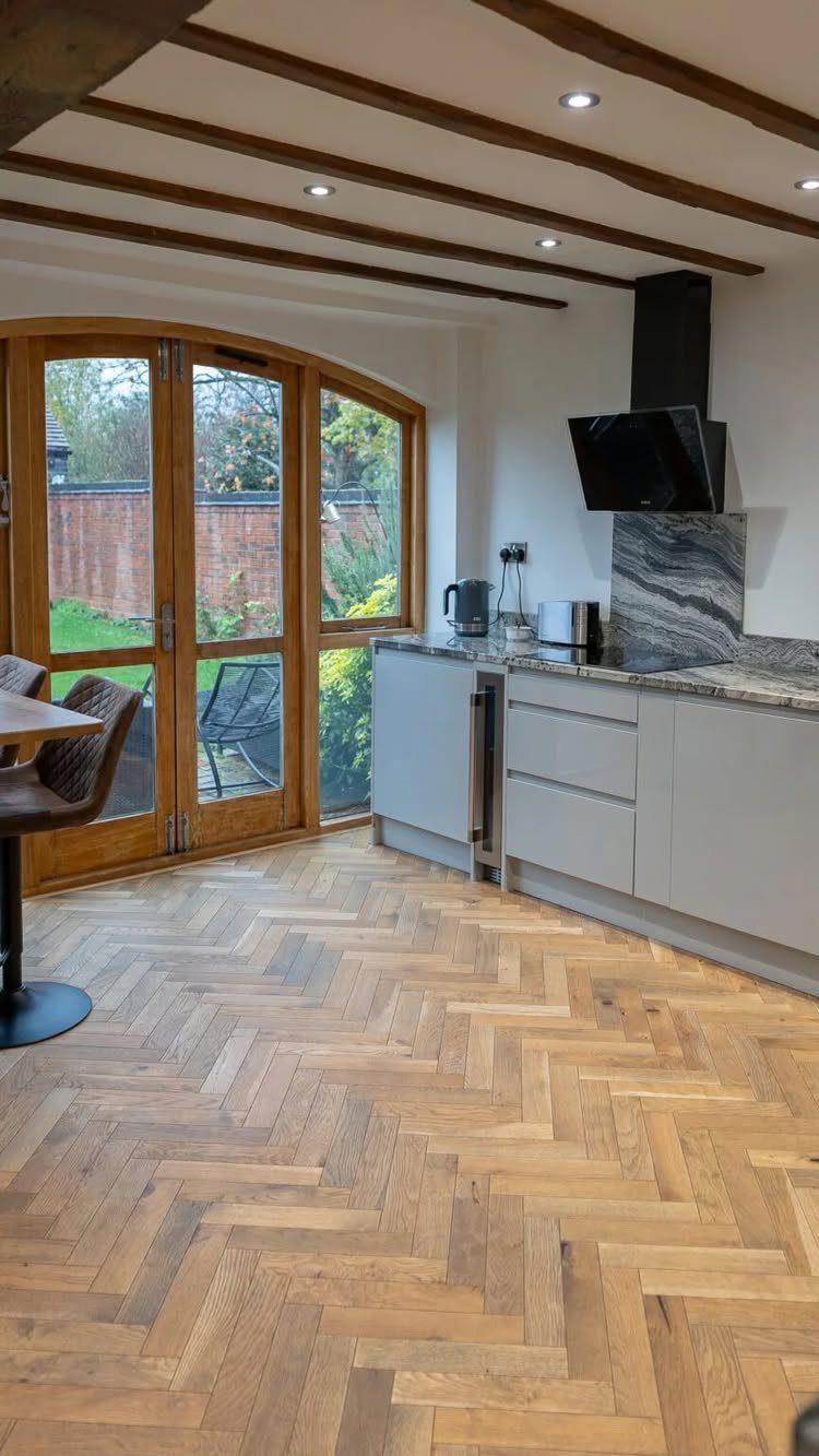 Light wood flooring in a herringbone pattern within a modern kitchen and dining space.