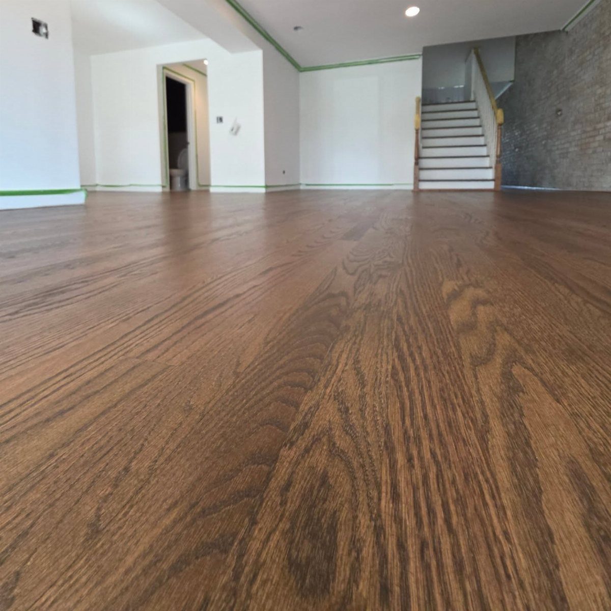 Medium brown stained wood flooring with visible grain texture in an empty room.