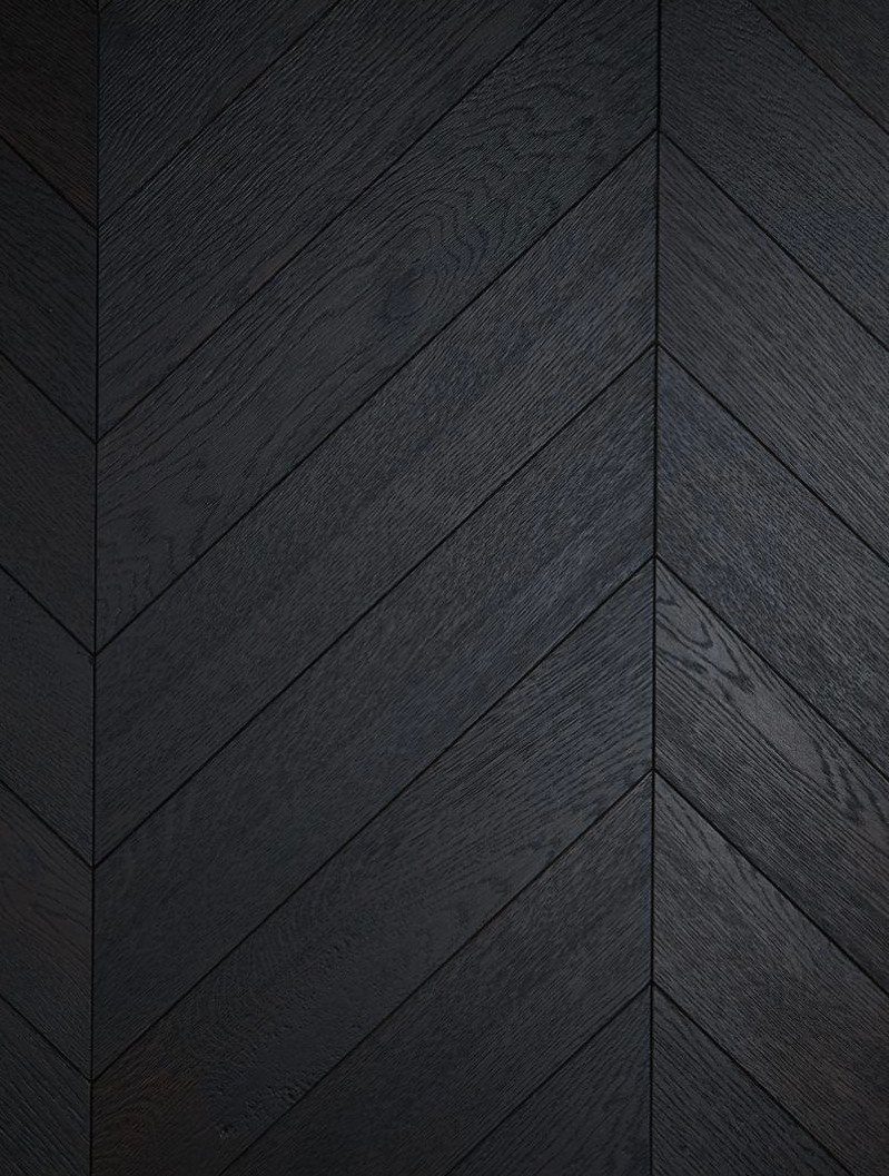 Black stained wood floor planks arranged in a herringbone pattern showing natural grain.