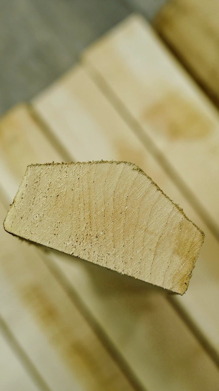 A close-up view of the end grain of a light-colored wooden plank.