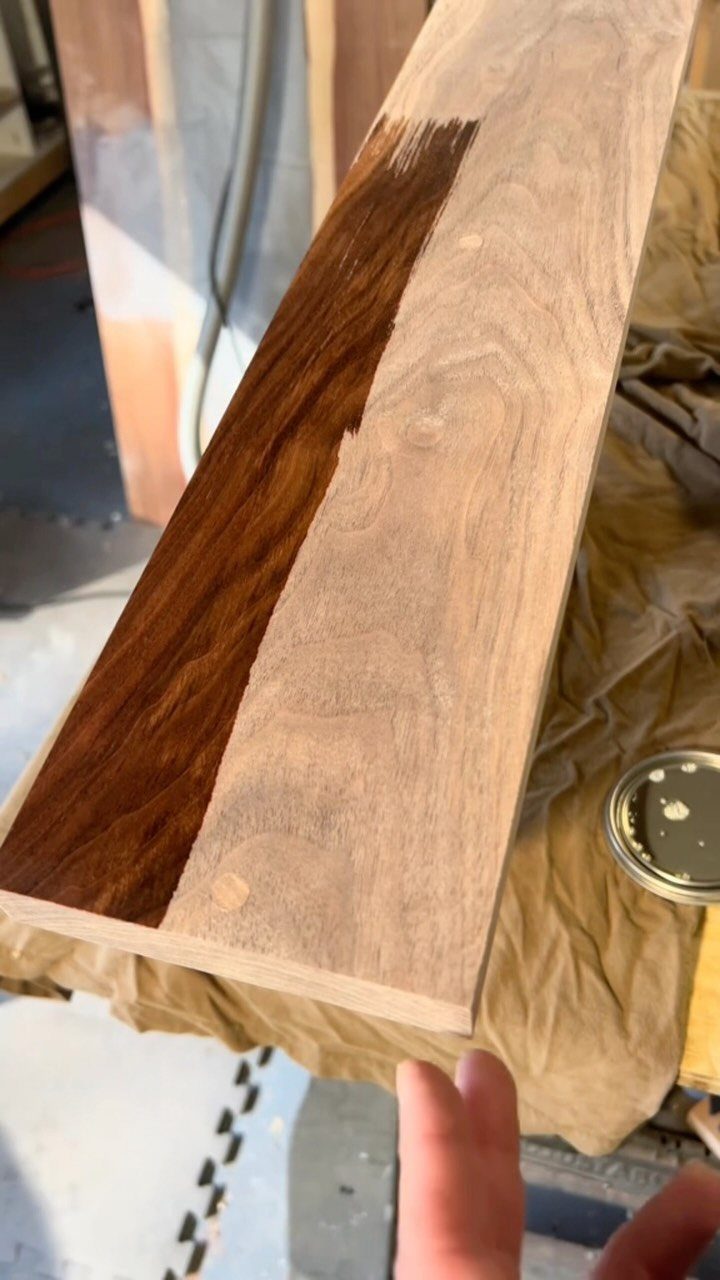 A wooden plank showing a contrast between natural light wood and dark stained wood grain.