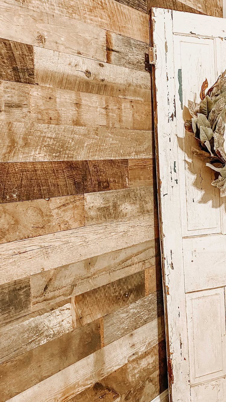 Wood Panelling on Walls: 8 Styles That Read as Architecture 8 Rustic wooden planks in varying brown tones covering a wall next to a white door.