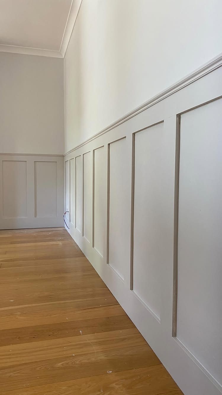 Wood Panelling on Walls: 8 Styles That Read as Architecture 5 White rectangular wood panelling installed on a wall above light wooden floorboards.