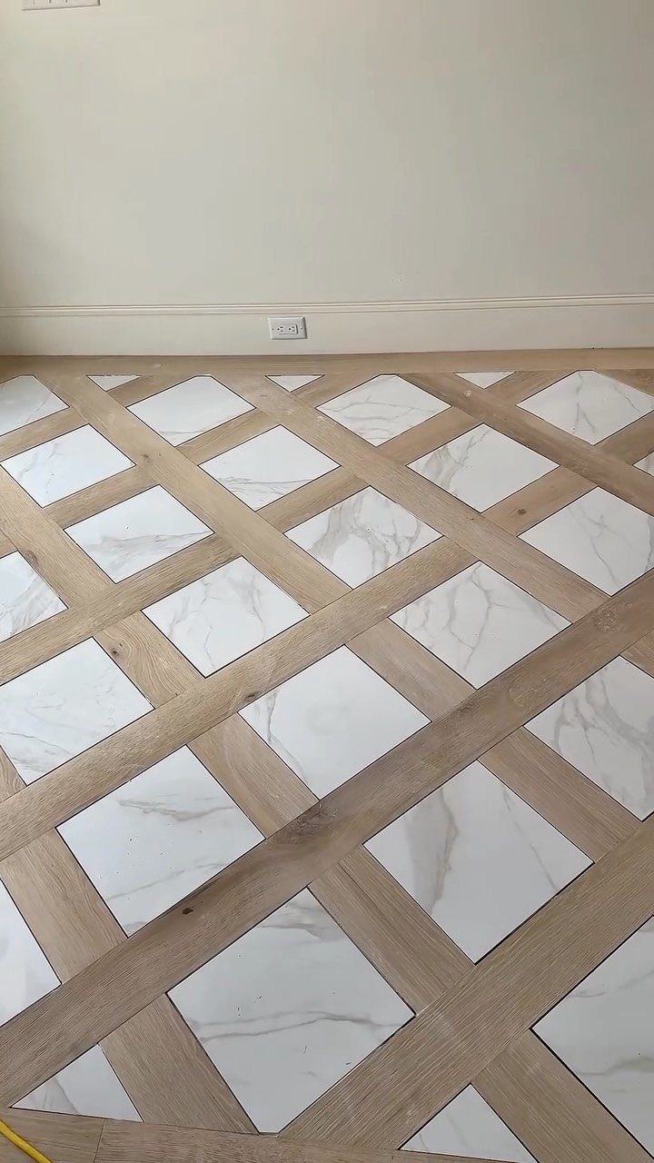 Geometric floor pattern with light wood planks and white marble tiles in a room.